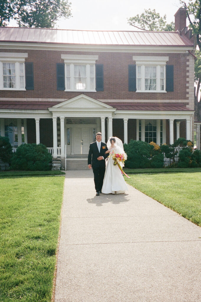 A film photo of the dad walking his daughter down the aisle.